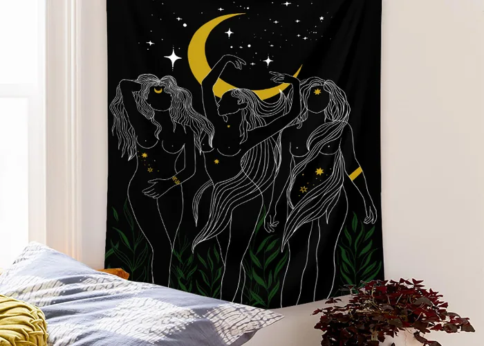 A black tapestry with three line drawn women dancing under a gold crescent moon, hung above a bed.